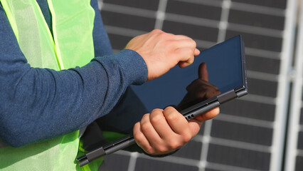 Black energy specialist using digital tablet reading information to check the efficiency of solar...