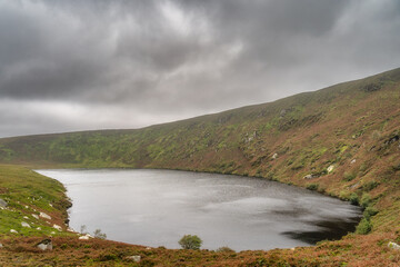 Lake, Lough Bray surrounded by mountains and covered in moody, dramatic storm clouds. Hiking in...