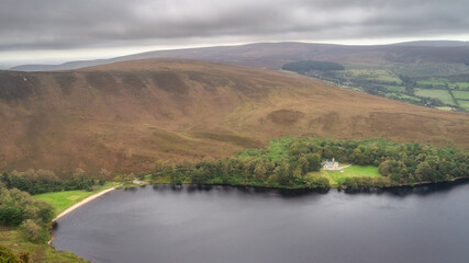 Mansion or house and beach hiding in small forest at the edge of lake Lough Bray, surrounded by...