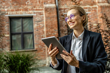 Cute young woman in black suit with a tablet in hands