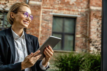 Cute young woman in black suit with a tablet in hands