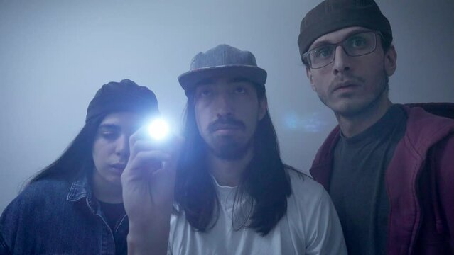 two young Latin men and a young Latin woman checking a power outage with a flashlight