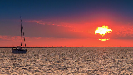 Orange sunset with sailboat - Camargue, Gard, France