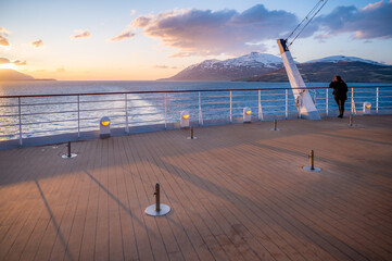 Sunset above Iceland snow mountains, sea in front, view from a cruise ship in the evening, boat...