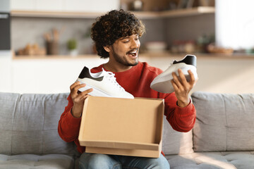 Happy excited indian man unboxing parcel with new shoes at home