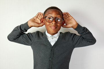 Horizontal portrait of cute funny african american boy in round-shaped glasses eavesdropping with...