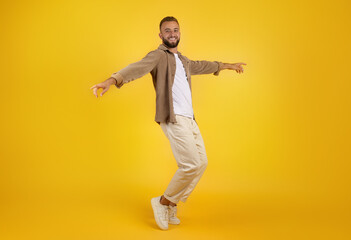 Fototapeta na wymiar Smiling millennial caucasian guy with beard in casual has fun, dance, freezes in air
