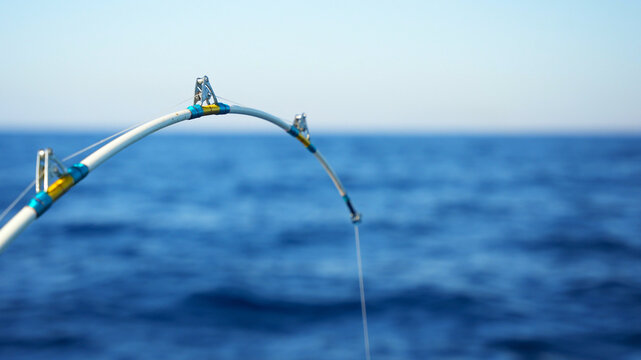 Close up of bent fishing rod for the big catch in holder on a motor boat in the sea