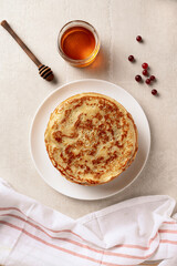 Crepes, thin pancakes with honey on a white plate. Marble background. Top view.