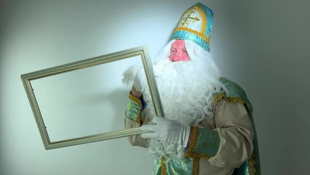 saint nicholas draws in an empty frame with a beautiful white pen a fabulous letter magical action he has a white fluffy beard a suit blue with gold he comes before santa claus Christmas