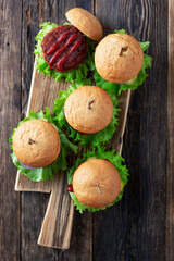 Tasty grilled home made burgers with beef, tomato, cheese, cucumber and lettuce, Top view with copy space