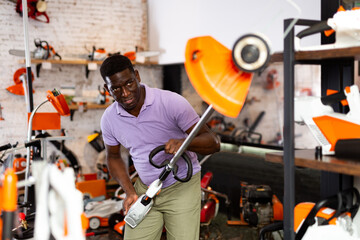 African-american man choosing strimmer in gardening tools store.
