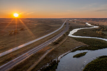 sunrise over a river meandering through Nebraska Sandhills, highway and railroad - aerial view of Middle Loup River near Halsey