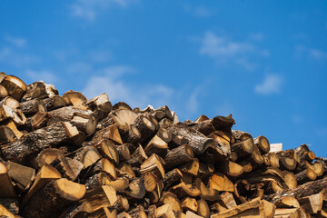 A lot of firewood against the blue sky, close-up photo.