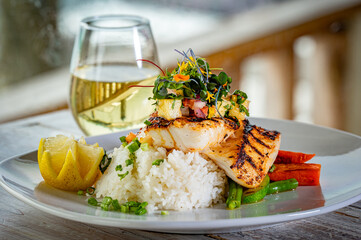 Blackened Black Grouper on a bed of rice and vegetables and topped with mango salsa and micro...