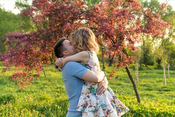This pic captures a young couple huggin' it out while strollin' through a bloomin' apple orchard....