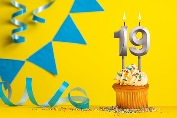 Lighted birthday candle number 19 - Yellow background with blue pennants