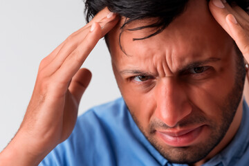 Fototapeta premium Man with black hair, brown eyes and blue shirt with severe headache