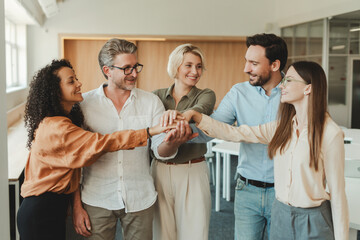 Group successful smiling people, workers, managers holding hands together standing in modern office