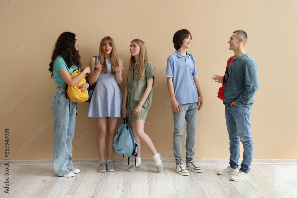 Wall mural Group of students with backpacks near beige wall