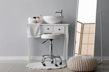 Interior of bathroom with sink bowl on dressing table, stool and mirror