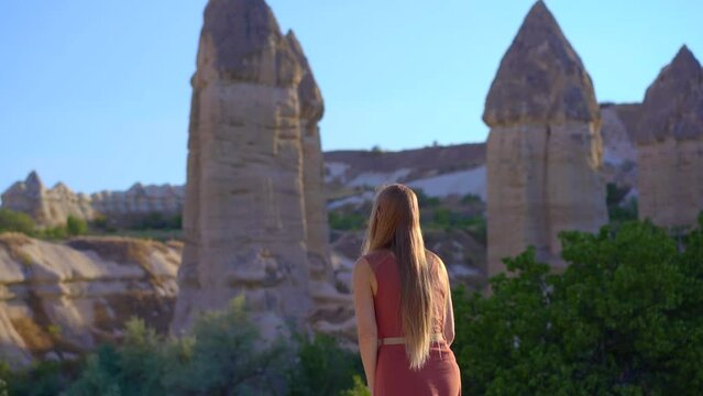 A young woman tourist visits the Love Valley in Cappadocia, Turkey, where nature's artistry has carved a surreal landscape of distinct-shaped rocks. These unique formations, shaped by centuries of