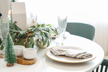 Festive table setting with white plate, cutlery and Christmas decorations