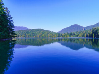 Pristine Sasamat Lake, BC, with mountain backdrop, viewed from the Sasamat Loop, forest trail on a clear late summer day.