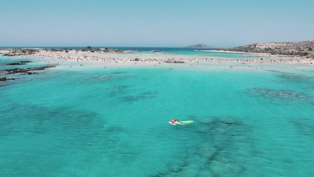 Leisure time spent on a sunny beach concept. Greek Elafonisi Beach seen from aerial view. Vivid turquoise clean seawater and tourist sunbathing. High quality 4k footage