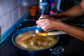 Someone unrecognizable chunks garlic to add to the broth