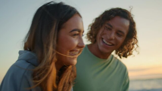 Teen couple laughing at sundown ocean shore date closeup. Happy lovers walking
