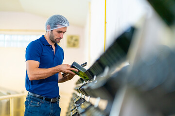 Caucasian man winemaker staff inspecting wine sediment in the bottle in modern wine factory. Winery...