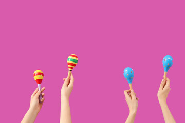Female hands holding maracas on pink background