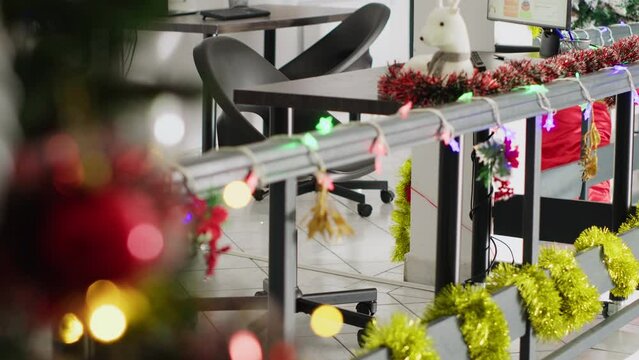 Christmas pine tree adorn with baubles and xmas lights in empty office. Business audit statistics on computer screens in xmas adorn workplace with no workers during winter holiday season