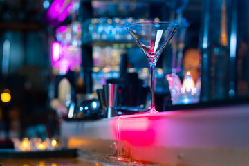 Professional male bartender preparing and serving cocktail drink to customer on bar counter at...