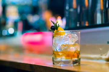 Professional male bartender preparing and serving cocktail drink to customer on bar counter at...