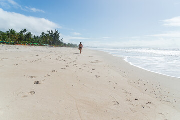 A Caucasian woman walking on the sands of a tropical beach in northeastern Brazil.