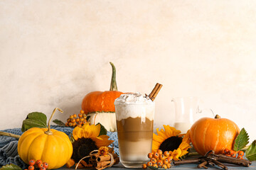 Glass of tasty pumpkin latte with cinnamon and star anise on blue wooden table