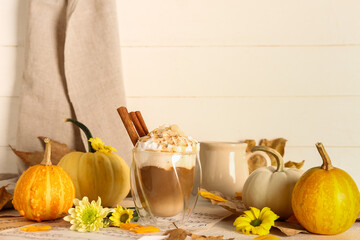 Obraz na płótnie Canvas Glass of tasty pumpkin latte with cinnamon and almond on white table