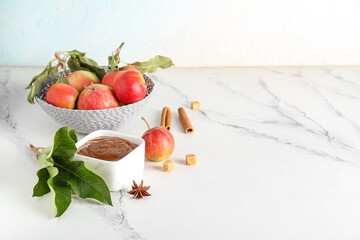 Bowl of sweet apple jam, fresh fruits and spices on light table