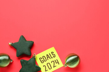 Sticky note with goals for 2024 and Christmas balls on red background