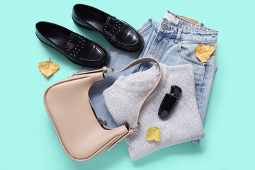 Composition with stylish female clothes, accessories and fallen leaves on color background
