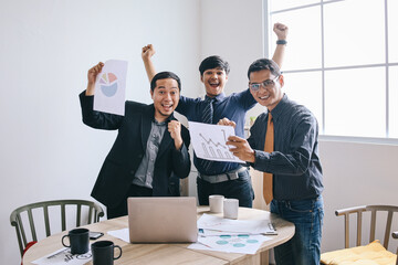 Group of Asian businessman looking at camera and raising hands showing victory gesture with happy expression.  Business people celebrating high profit of business