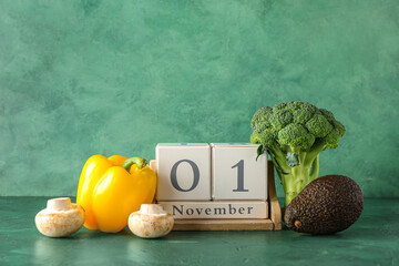 Healthy products and cube calendar with date NOVEMBER 1 green background. World Vegan Day concept