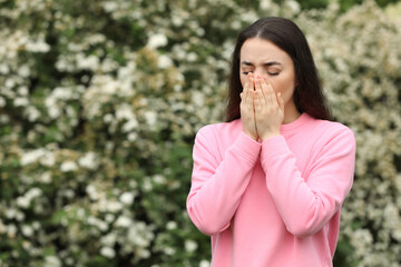 Woman suffering from seasonal spring allergy outdoors, space for text