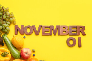 Date NOVEMBER 1 made of wooden letters with fresh vegetables and fruits on yellow background. World Vegan Day concept