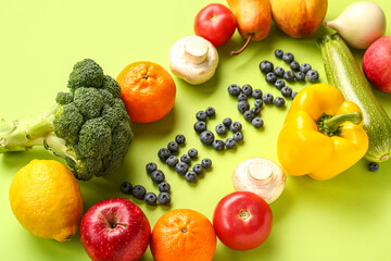 Word VEGAN made of blueberries with different fruits and vegetables on green background