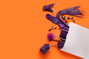 White shopping bag with sex toys on orange background
