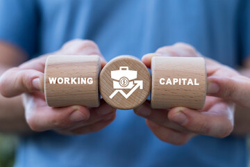 Hands holding wooden cylinders sees inscription: WORKING CAPITAL. Working capital business concept.