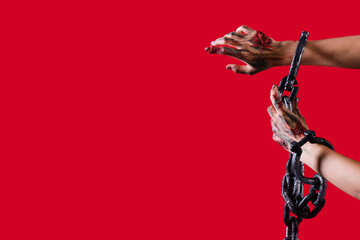Zombie hands with shackles on red background. Halloween celebration
